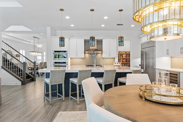 dining space with a notable chandelier, a towering ceiling, and light hardwood / wood-style floors