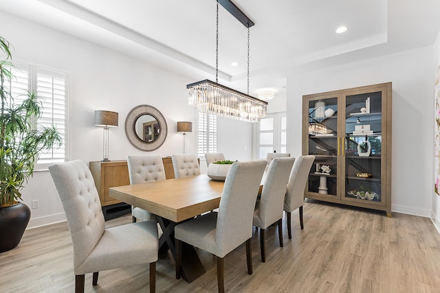 dining area featuring wood-type flooring and a raised ceiling