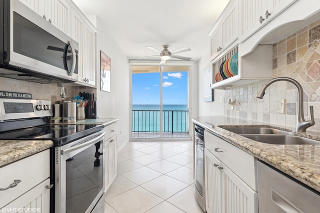 kitchen featuring sink, stainless steel appliances, white cabinets, and a water view