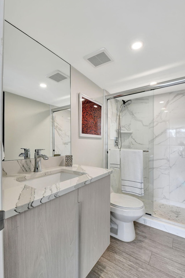 bathroom with vanity, a shower with shower door, and toilet