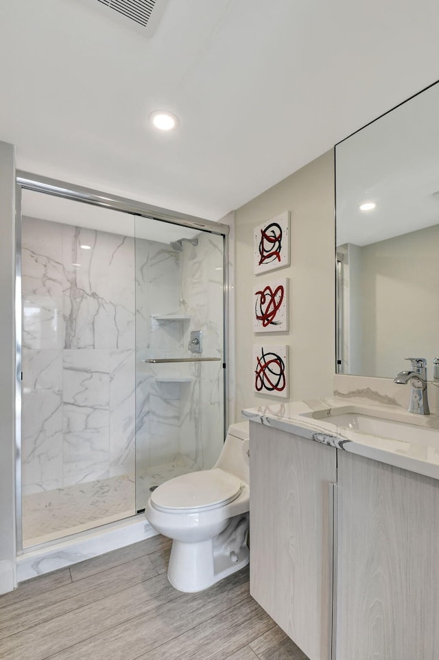 bathroom featuring walk in shower, vanity, toilet, and hardwood / wood-style floors