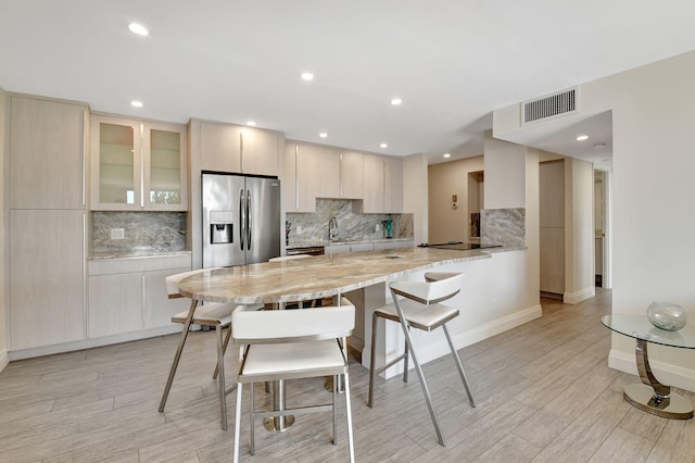 kitchen with sink, stainless steel fridge with ice dispenser, a breakfast bar area, and backsplash