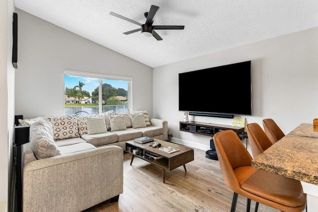 living room with hardwood / wood-style flooring, vaulted ceiling, ceiling fan, and a textured ceiling