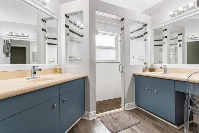 bathroom featuring vanity, hardwood / wood-style floors, a textured ceiling, and a shower with shower door