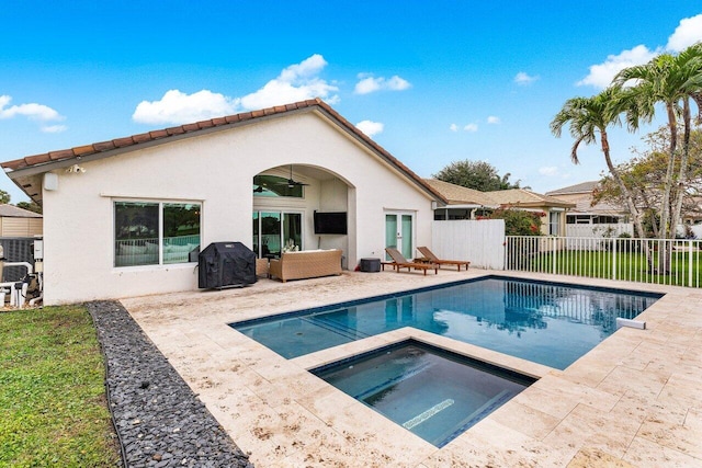 rear view of property featuring a patio, ceiling fan, and a pool with hot tub