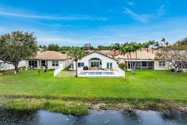 back of house with a water view, a sunroom, and a lawn