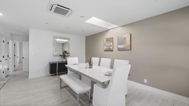 dining space featuring a skylight and light wood-type flooring