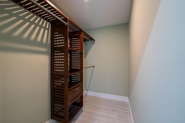 walk in closet with light hardwood / wood-style floors