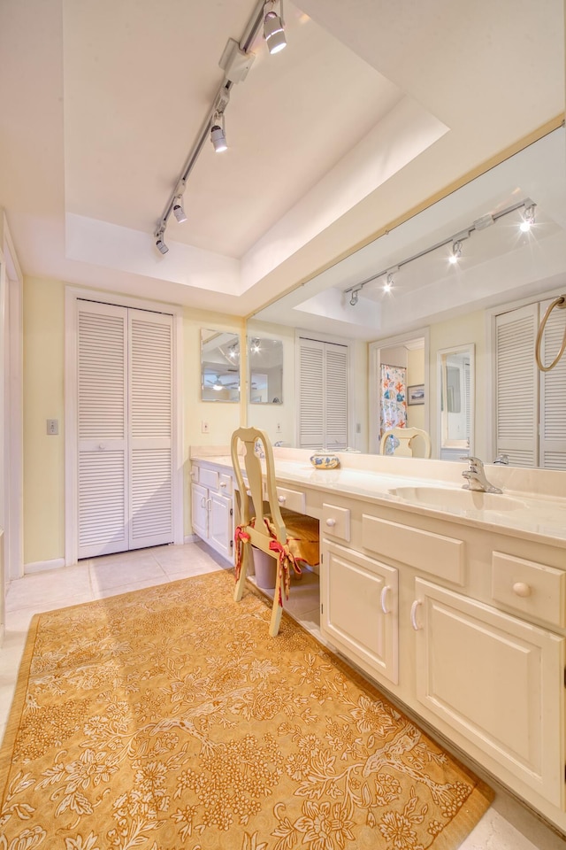 bathroom featuring tile patterned flooring, vanity, track lighting, and a raised ceiling