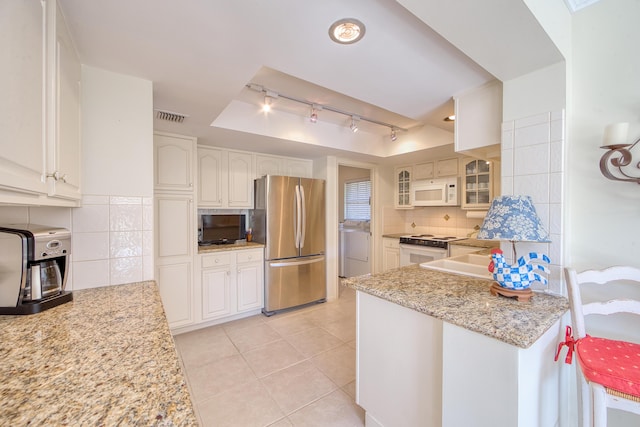 kitchen featuring tasteful backsplash, white cabinetry, light stone counters, and white appliances