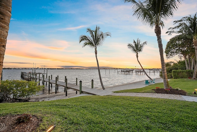 view of dock with a yard and a water view