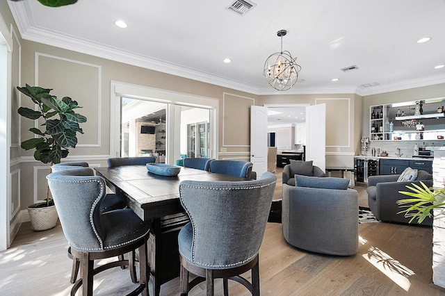 dining space with visible vents, bar, light wood-style floors, and ornamental molding