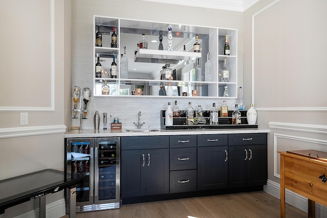 bar with backsplash, wine cooler, indoor wet bar, light wood-style floors, and a sink