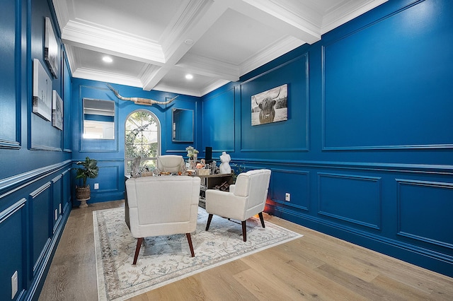 interior space featuring crown molding, beamed ceiling, wood finished floors, a decorative wall, and coffered ceiling