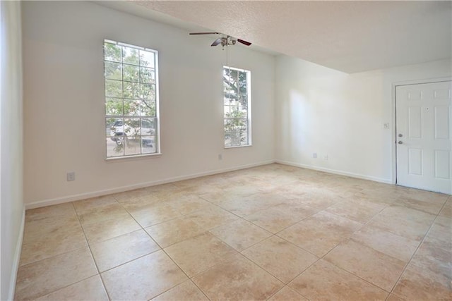 tiled spare room with a textured ceiling and ceiling fan