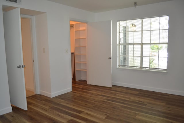 unfurnished bedroom with a walk in closet, dark wood-type flooring, and a closet