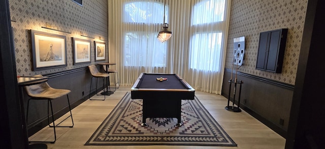 game room with pool table, light wood-type flooring, and a high ceiling