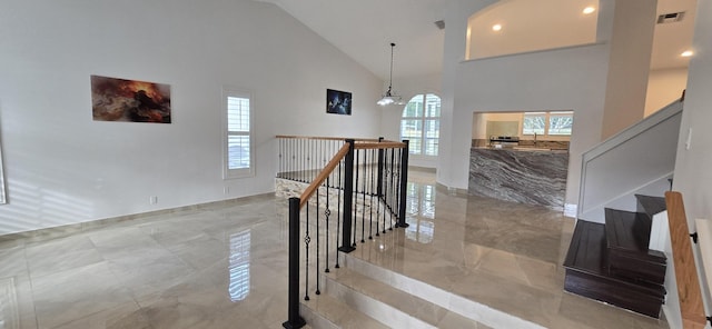 staircase with an inviting chandelier and high vaulted ceiling