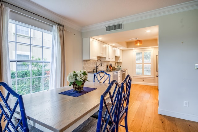 dining space with ornamental molding, sink, and light wood-type flooring