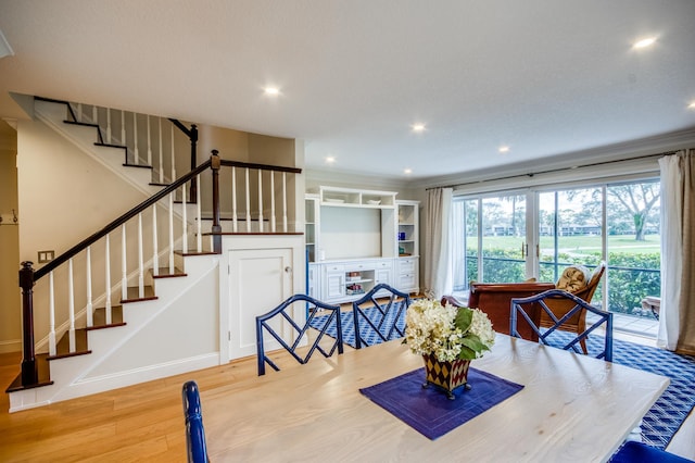 dining space with crown molding and light hardwood / wood-style floors