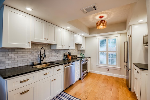 kitchen with sink, hanging light fixtures, stainless steel appliances, light hardwood / wood-style floors, and white cabinets