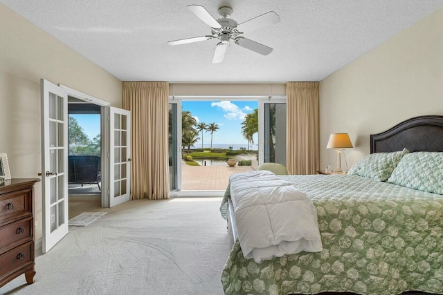 carpeted bedroom with access to exterior, french doors, a textured ceiling, and ceiling fan