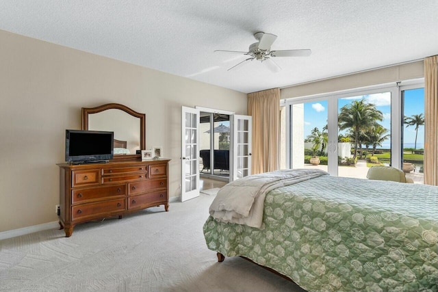 bedroom featuring ceiling fan, access to exterior, a textured ceiling, light colored carpet, and french doors