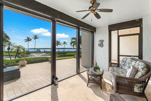 sunroom with ceiling fan and a water view