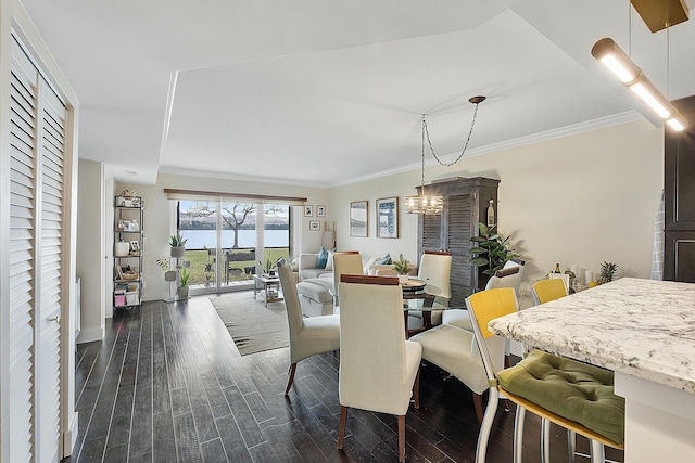 dining space featuring dark hardwood / wood-style flooring, crown molding, an inviting chandelier, and a water view