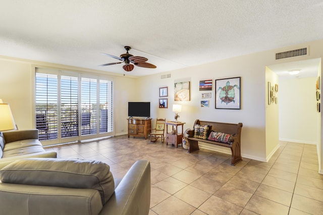 living room with ceiling fan, a textured ceiling, and light tile patterned floors