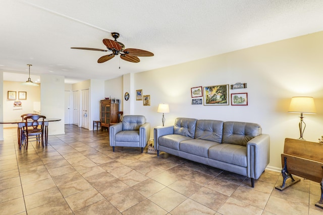 living room with ceiling fan, a textured ceiling, and light tile patterned floors