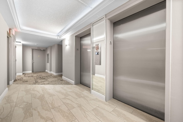 hallway featuring elevator, a raised ceiling, a textured ceiling, and baseboards