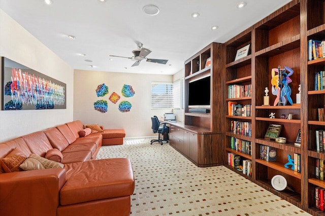 office space featuring built in desk, light colored carpet, and ceiling fan