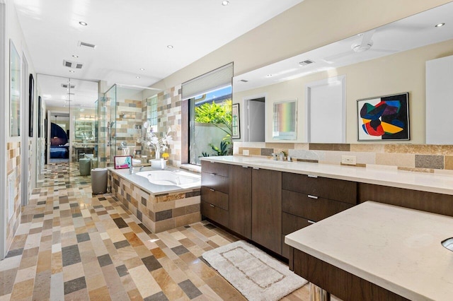 bathroom featuring vanity, tasteful backsplash, and shower with separate bathtub