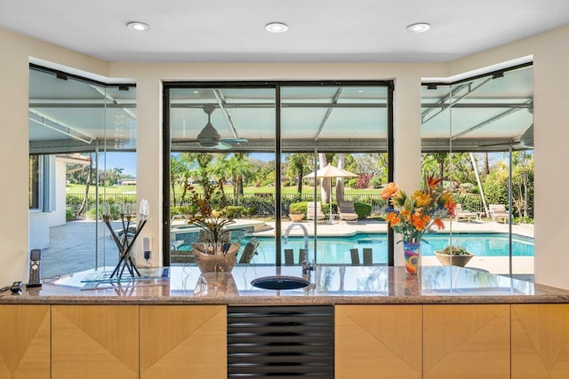 bar featuring wine cooler, sink, and stone counters