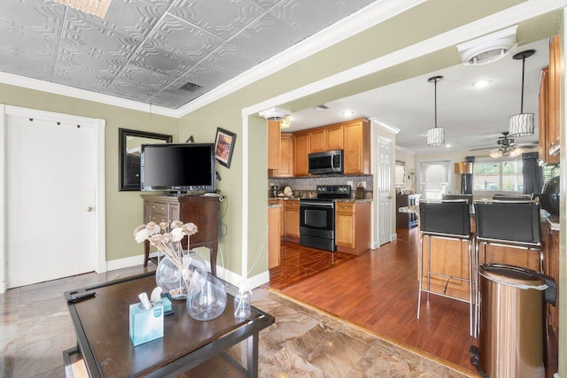 living area with an ornate ceiling, visible vents, ornamental molding, ceiling fan, and baseboards