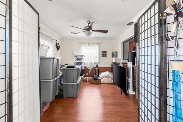 office area featuring a textured ceiling, dark wood-type flooring, a ceiling fan, visible vents, and ornamental molding