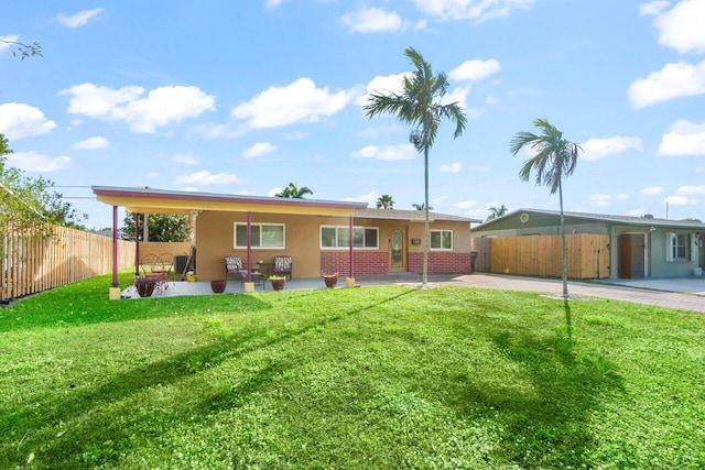 rear view of house with a yard, a patio area, brick siding, and fence