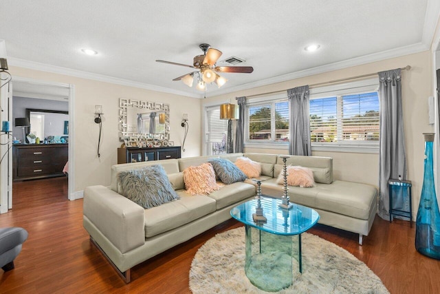 living room featuring ceiling fan, visible vents, baseboards, dark wood finished floors, and crown molding