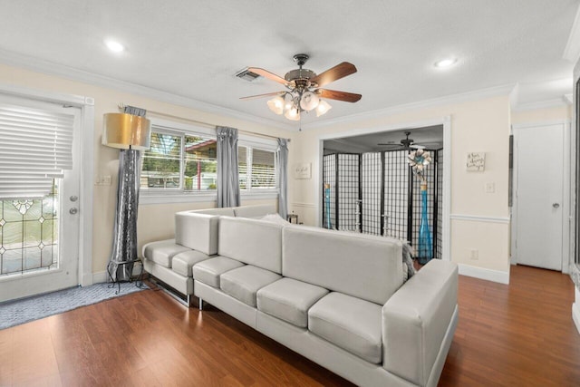 living area featuring dark wood-style floors, visible vents, ornamental molding, and baseboards