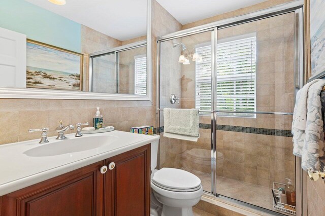 bathroom with walk in shower, toilet, tasteful backsplash, tile walls, and vanity