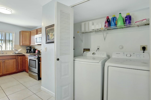 laundry room featuring light tile patterned floors, washing machine and dryer, and sink