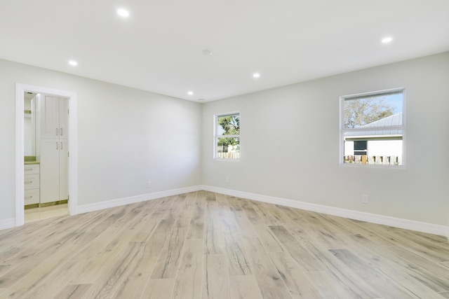 spare room with baseboards, light wood-type flooring, and recessed lighting