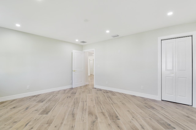 unfurnished bedroom featuring recessed lighting, a closet, visible vents, light wood-style flooring, and baseboards