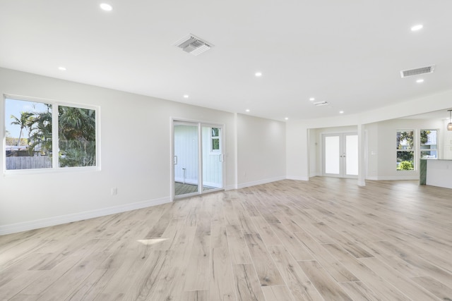 unfurnished living room with recessed lighting, visible vents, baseboards, light wood-style floors, and french doors