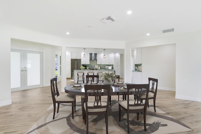 dining area with french doors, light wood-type flooring, and visible vents