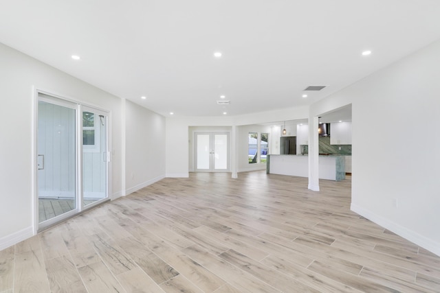 unfurnished living room with baseboards, visible vents, french doors, light wood-style floors, and recessed lighting