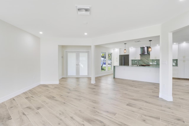 unfurnished living room with french doors, light wood finished floors, recessed lighting, visible vents, and baseboards