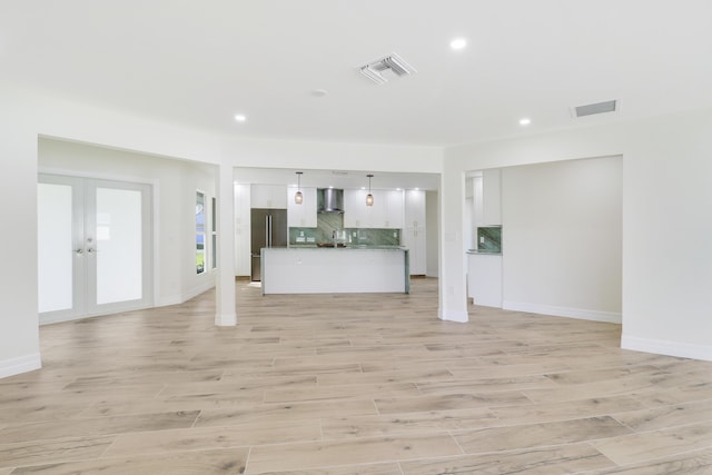 unfurnished living room featuring light wood finished floors, visible vents, and french doors