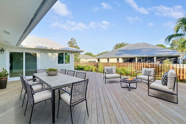 wooden terrace featuring fence, outdoor dining space, and an outdoor living space with a fire pit